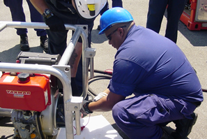 Coast Guard member attaching hydraulic lines to Fast Sweep Boom Prime Mover